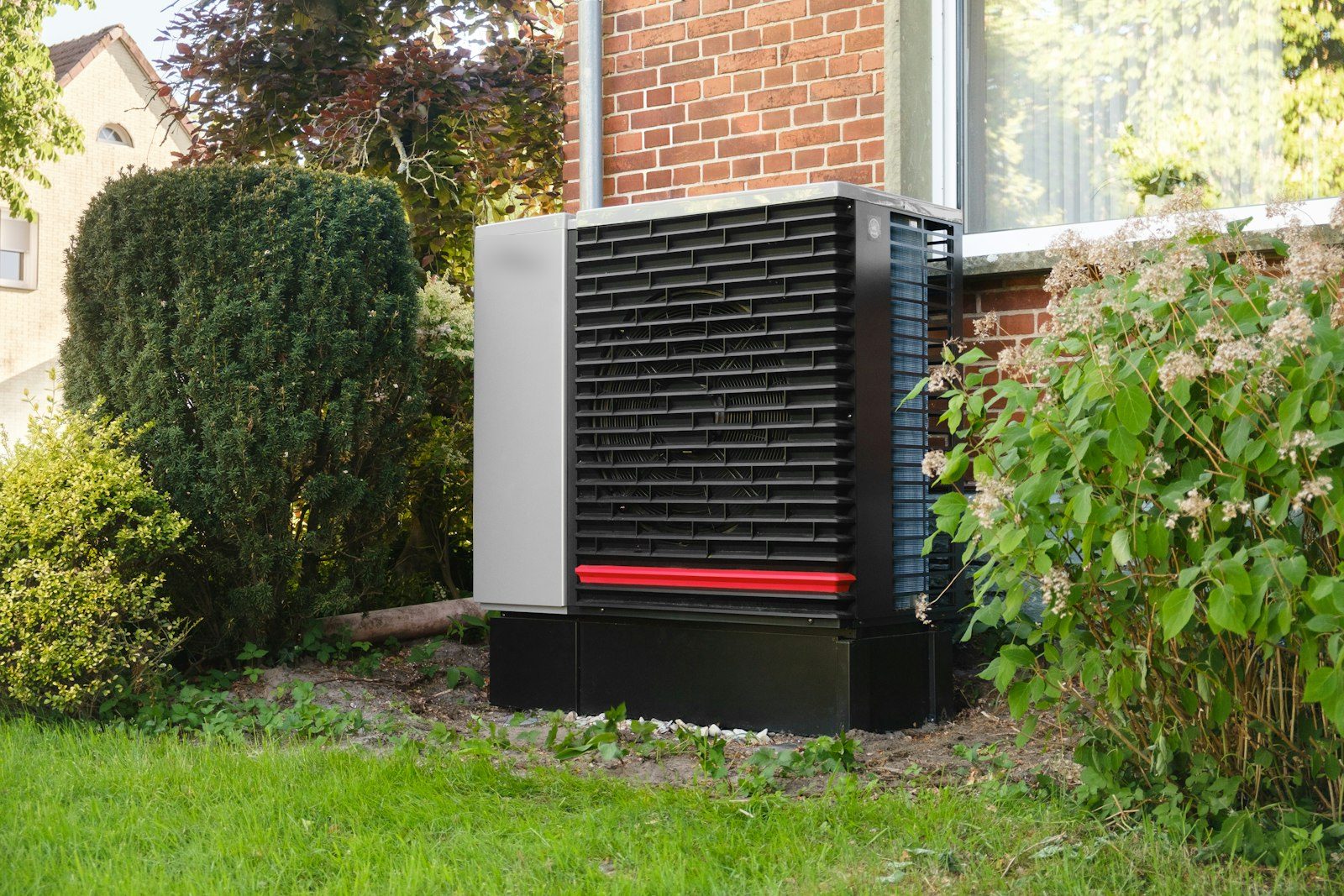 Outdoor heat pump unit beside a brick home